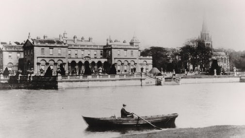 Looking across the lake to Clumber House and the Chapel. A man is rowing in a boat on the lake